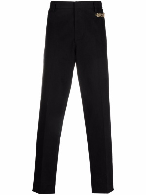 

Logo embellished tailored trousers, Moschino Logo embellished tailored trousers